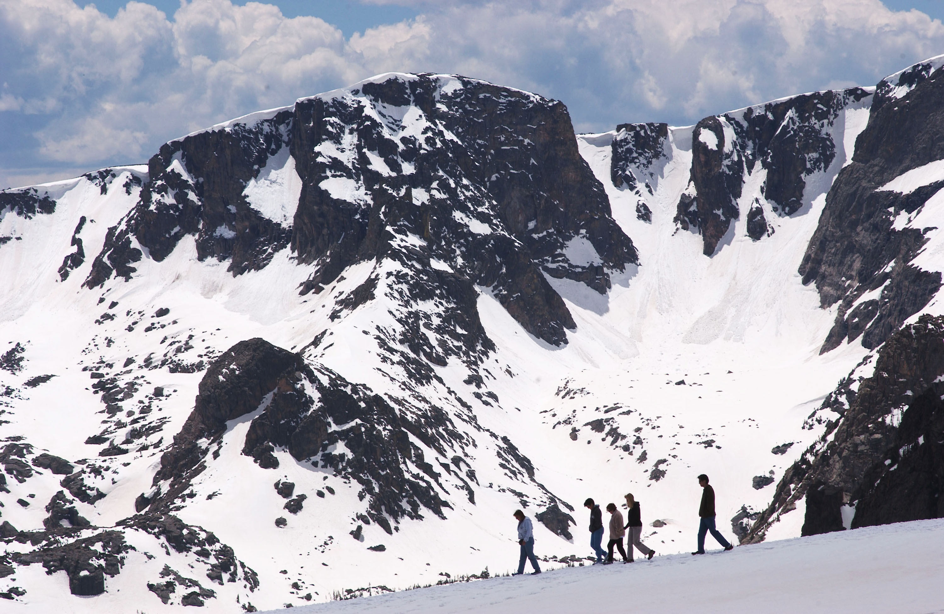 People walk near the Trail Ridge Road May 23, 2003 in Rocky Mountain National Park, Colorado. The road was opened for the season May 23 after crews spent a month plowing through the 15-foot-deep snowdrifts. Rising to an altitude of 12,183 feet above sea level the road is the highest contiguous paved highway in the country. The park is anticipating It's third busiest weekend, next to the Fourth of July and Labor Day. (Photo by Kevin Moloney/Getty Images)