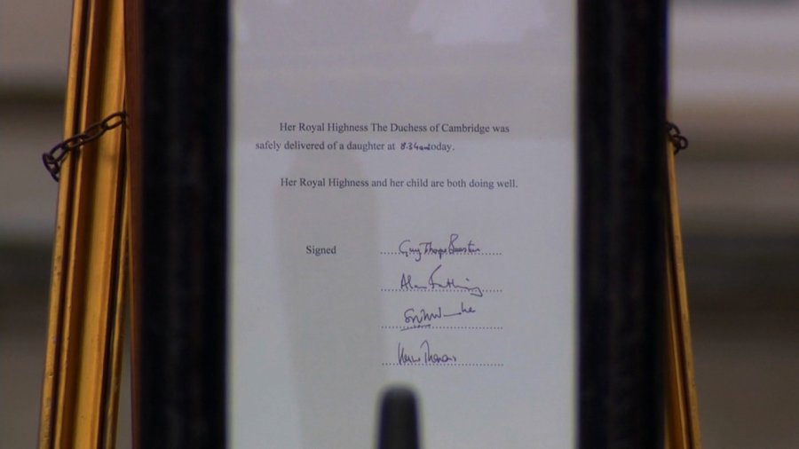 Crowds swarm outside the gates of Buckingham Palace on May 2, 2015, as the official royal birth announcement is placed on an easel.