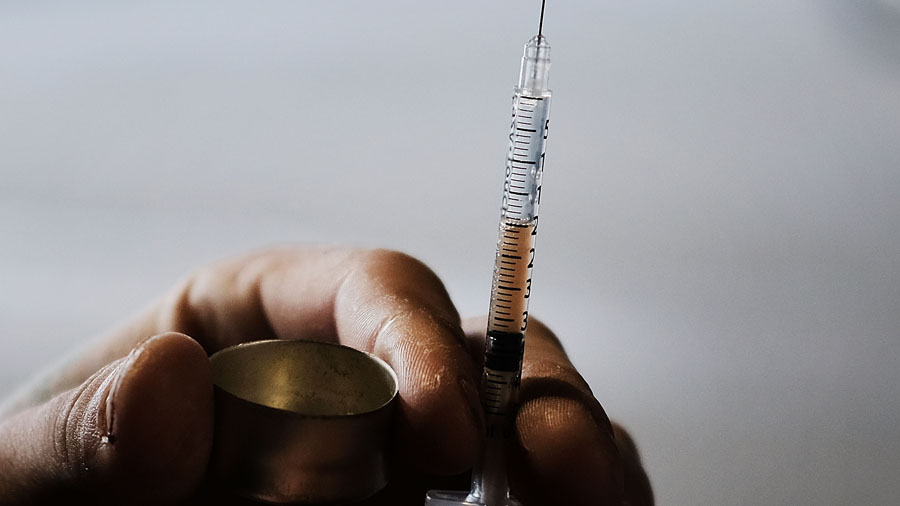 A man uses heroin under a bridge