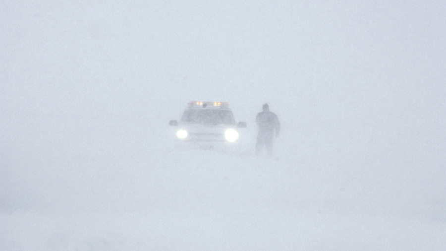 A worker with airport operations tries to navigate white out conditions at Denver International Airport