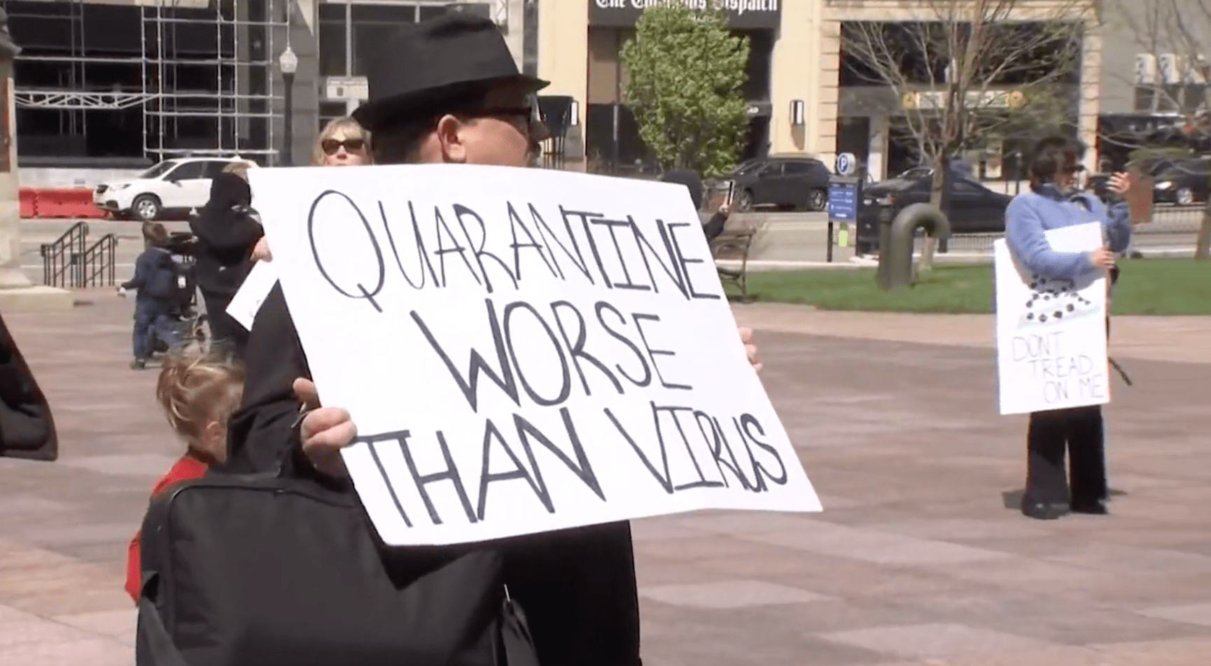 A man holds a sign that reads - quarantine worse than virus.