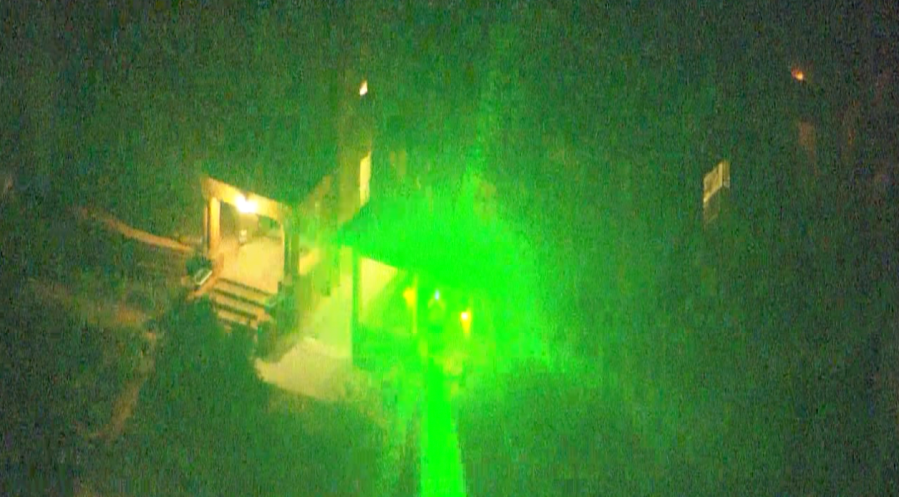 A green laser shines from a building toward the camera lens