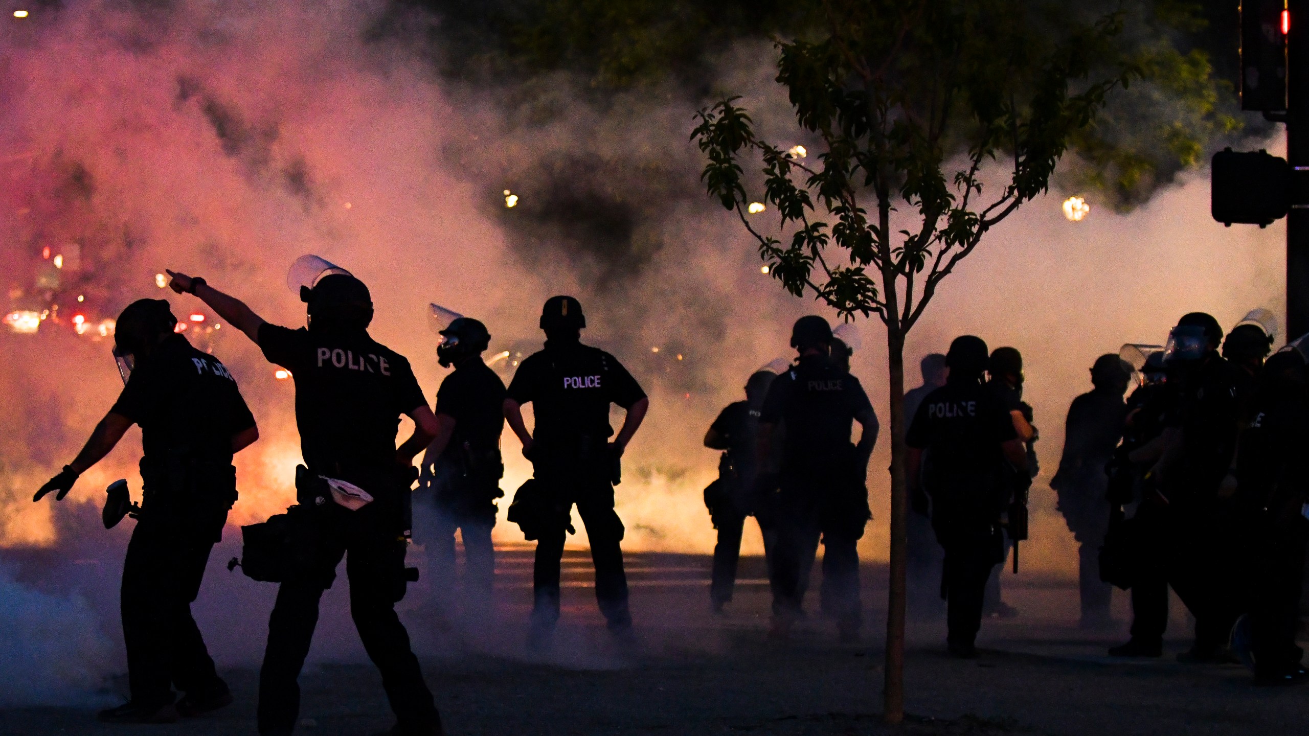 Police officers fire tear gas at protesters near the Colorado state capitol during a protest at night