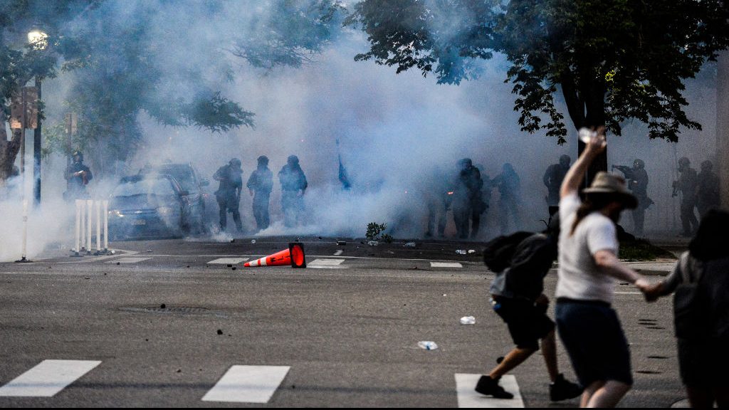 Police officers stand behind a wall of tear gas smoke after they attempt to disperse people marching along Colfax Ave. in Denver during the fourth consecutive day of protests in the aftermath of the death of George Floyd on May 31, 2020.