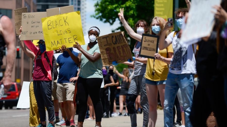 People hold signs near the Colorado State Capitol during the fifth consecutive day of demonstrations in the aftermath of the death of African American George Floyd on June 1, 2020 in Denver.