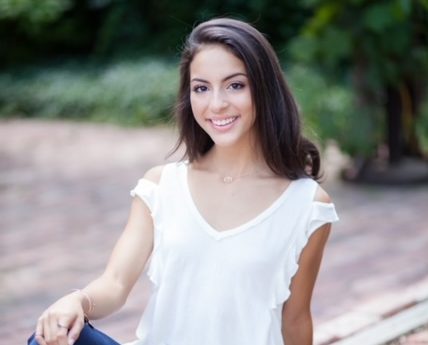 A young woman in a white shirt poses for a portrait