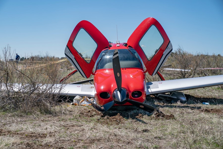 A close up of a small red and white airplane on dry dirt with its two doors lifted open on a field of dry dirt up of a small red and white airplane on dry dirt with its two doors lifted open on a field of dry dirt with blue sky