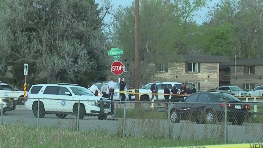 Police vehicles line the road along Federal Boulevard with apartments in the background