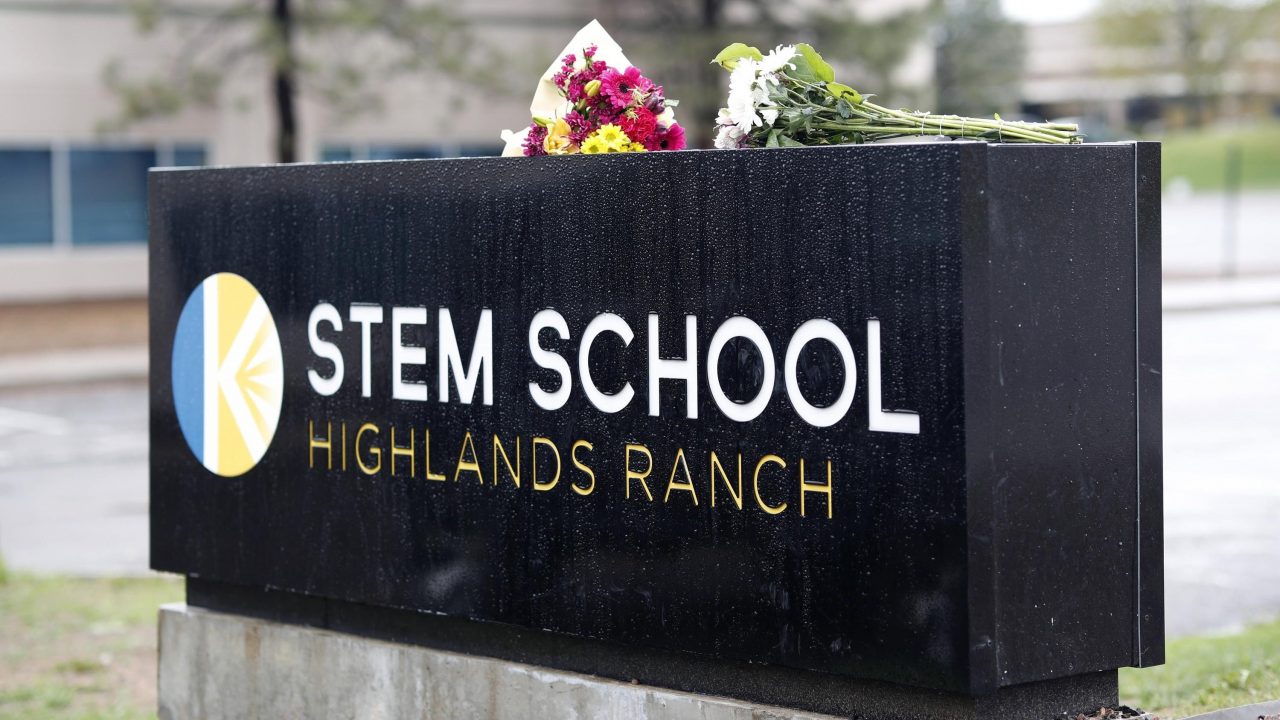 In this May 8, 2019 file photo bouquets of flowers sit on the sign outside the STEM School Highlands Ranch in Highlands Ranch, Colo.