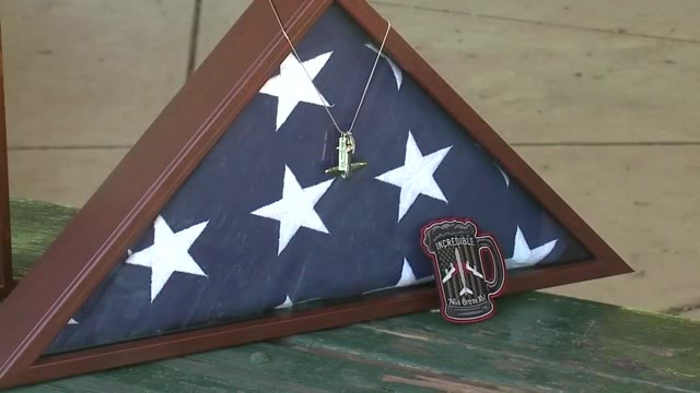 A U.S. flag folded and framed with tags hanging from it and a patch in front