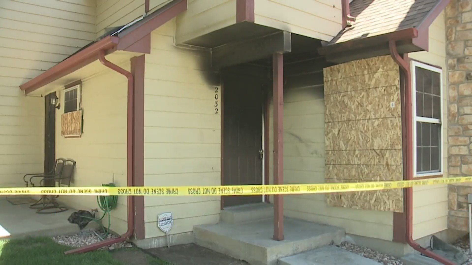 Caution tape in front of townhome close-up with burn marks around the door