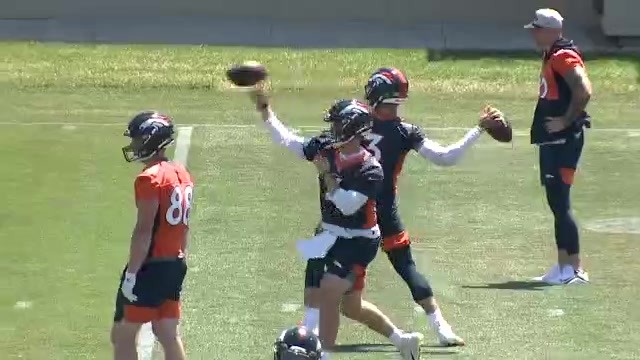 2 football players throwing footballs on a football field while in practice uniforms