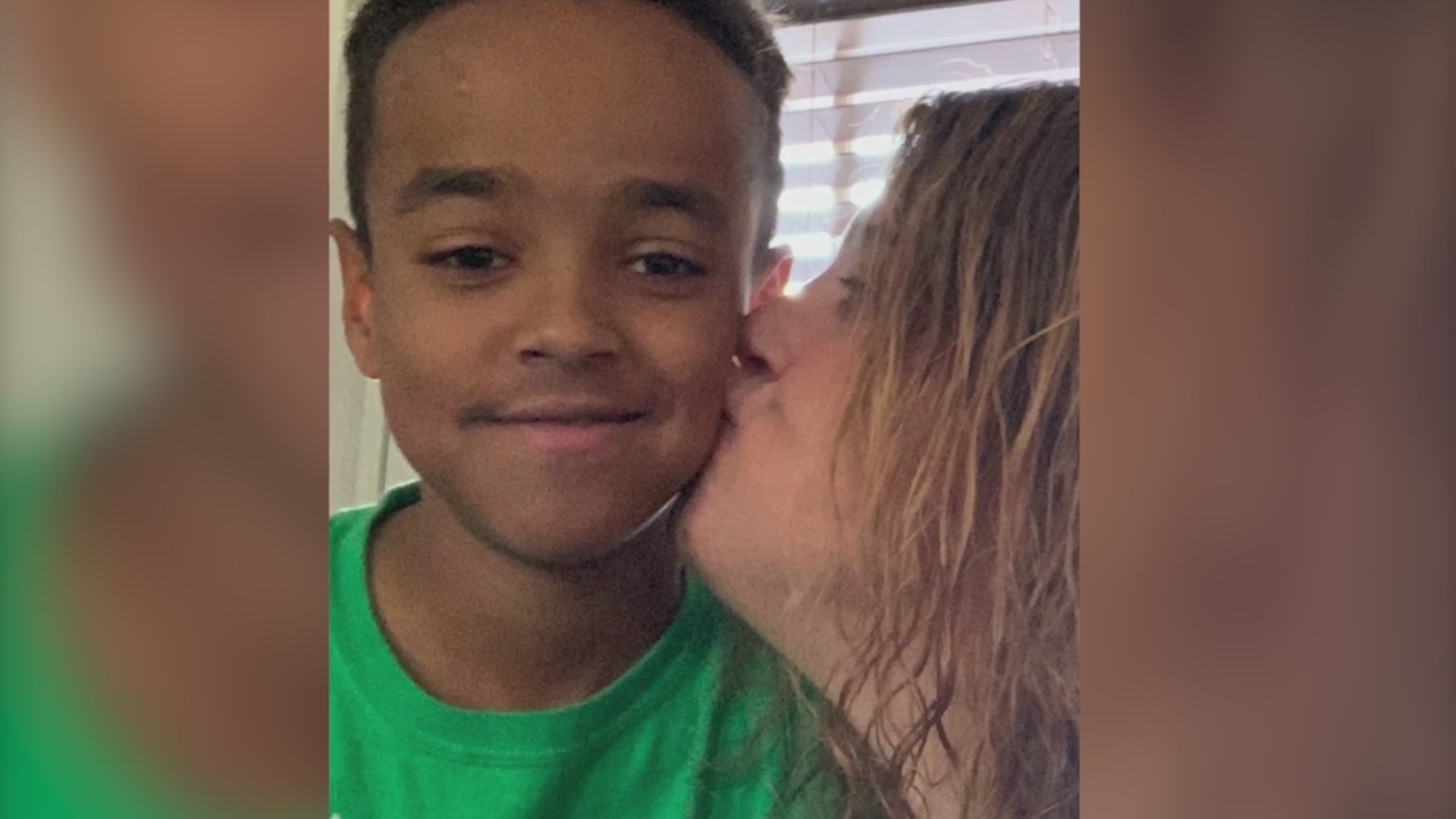 A young boy getting a kiss on the cheek from a woman