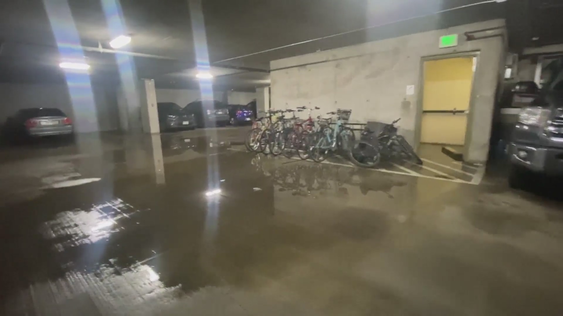 A flooded underground parking garage with bicycles and cars