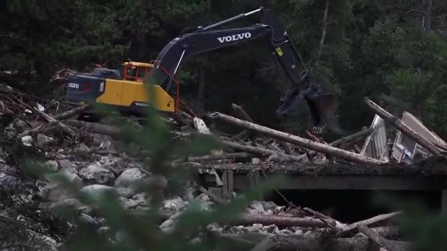 Heavy machinery removing knocked over trees and structure materials