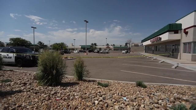 Crime scene tape wrapped around a strip mall parking lot in daylight