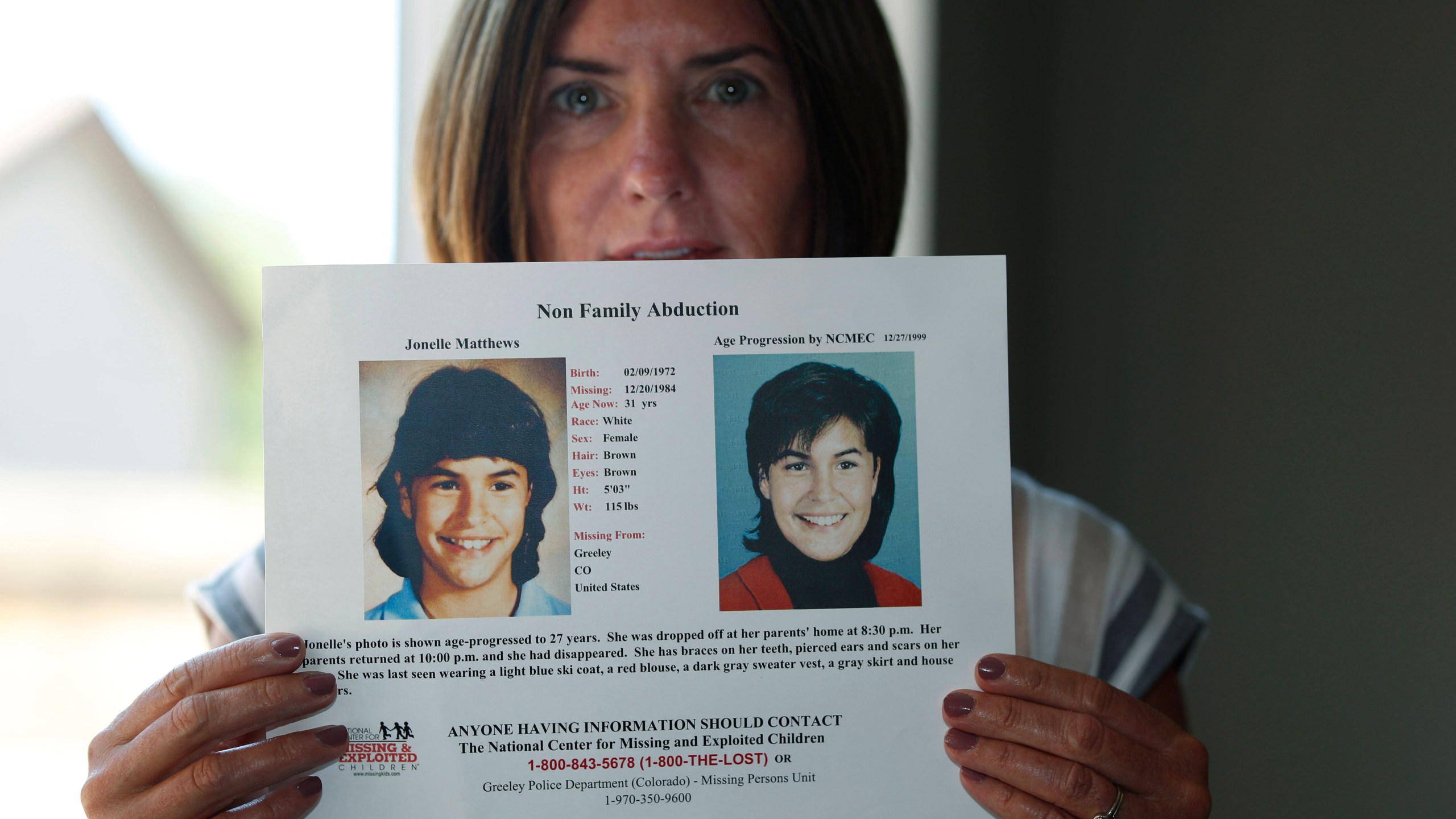 Jennifer Mogensen holds a poster of her adopted sister, Jonelle Matthews