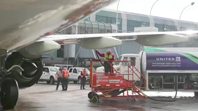 Airline crew member putting fuel in jet engine