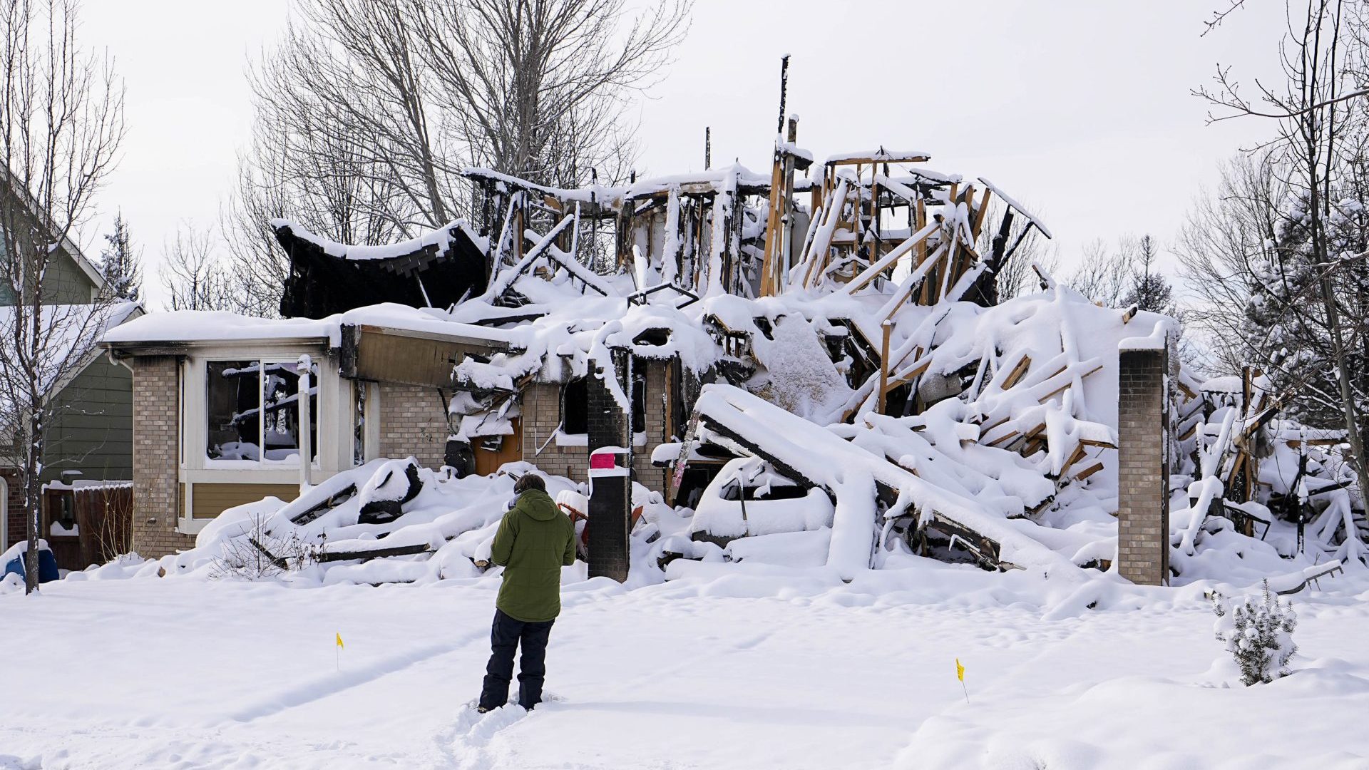 Snow covers the burned remains of a home