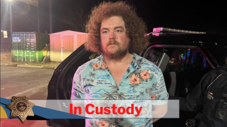 Casey Devol in tropical shirt in police custody at night