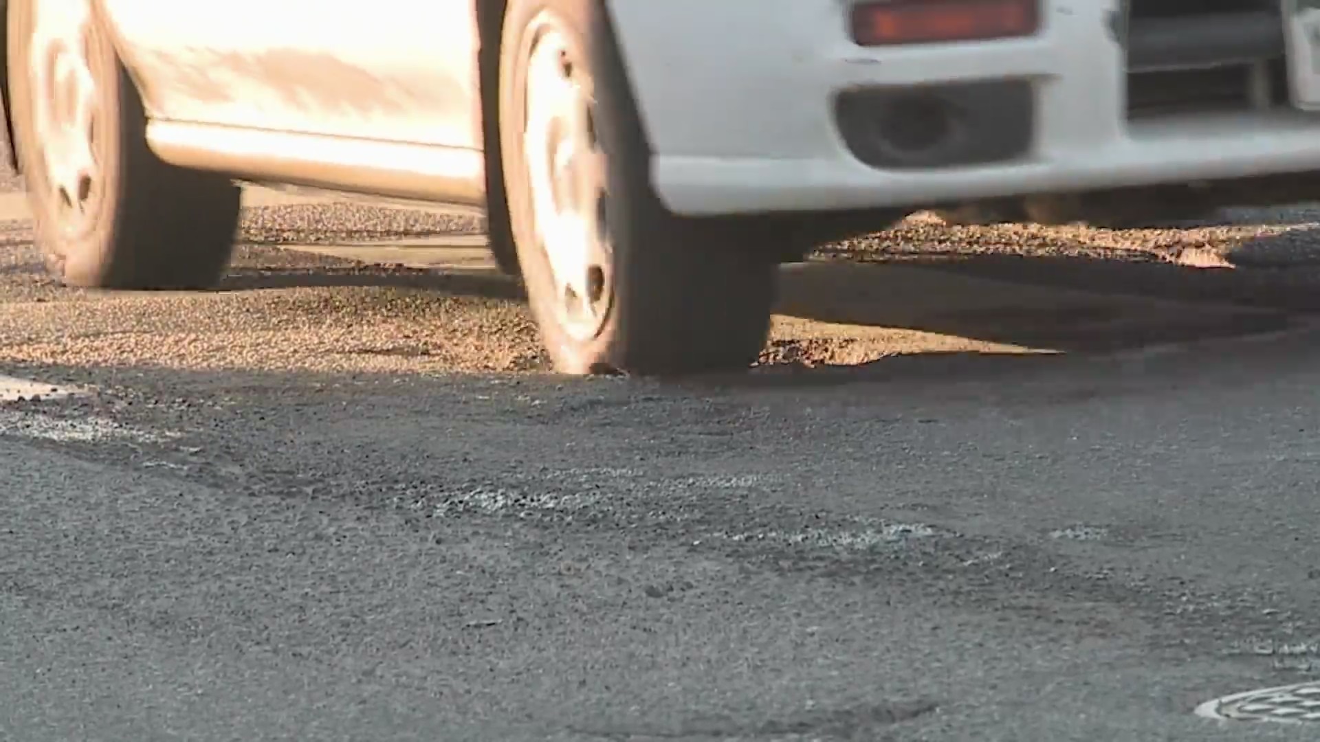 A vehicle rolling over a pothole on a road