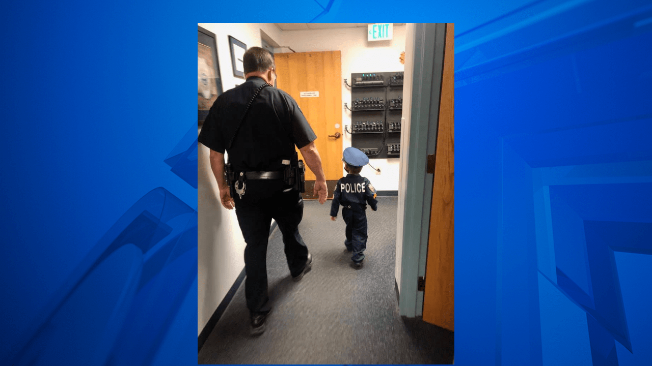 A police officer and a child side by side with their backs turned