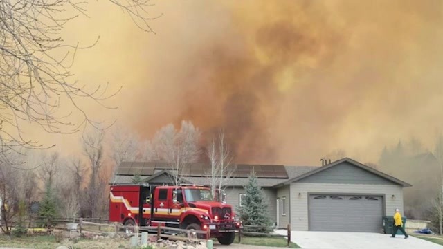 Smoke billows behind a home where a fire truck has a responded