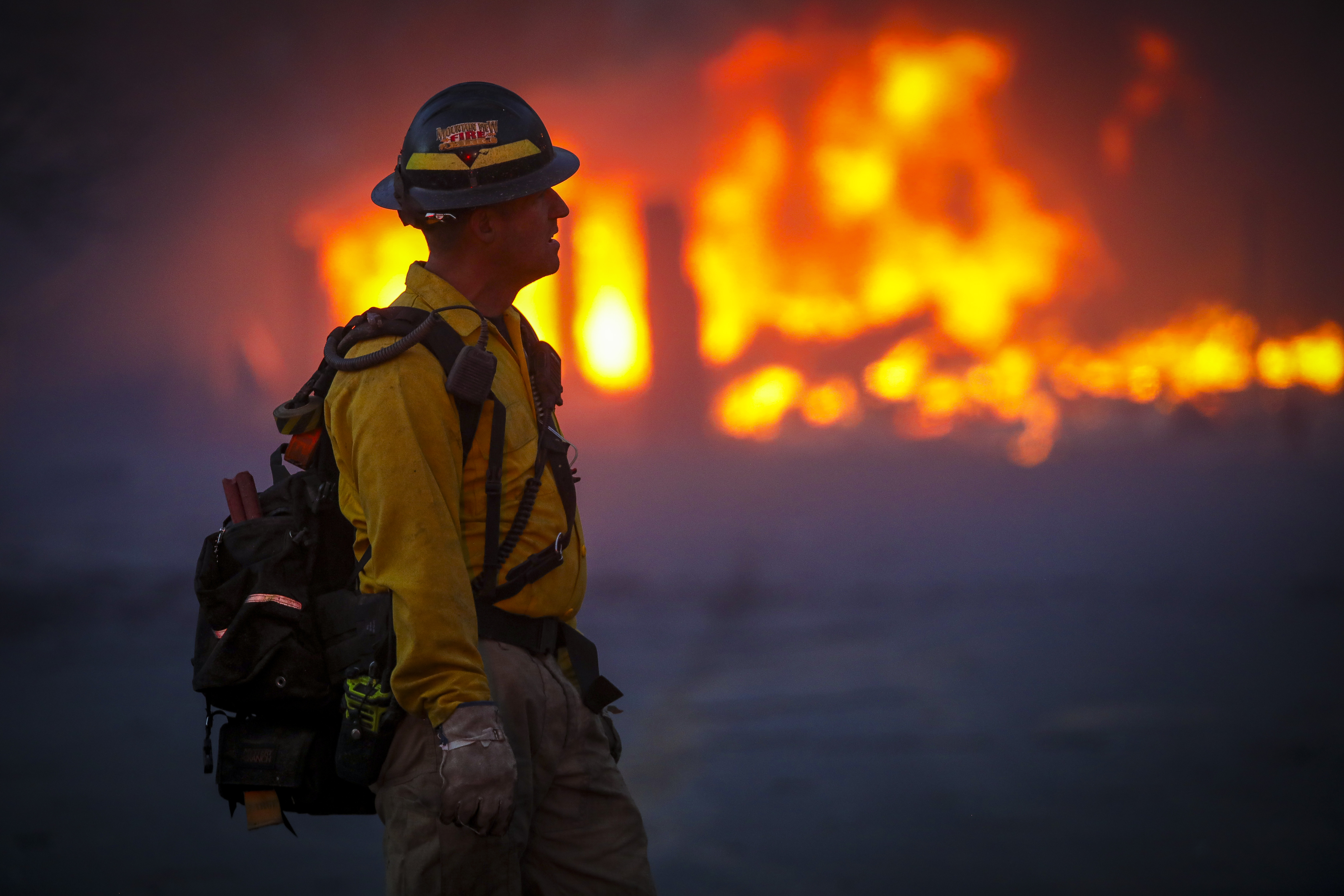 A Mountain View wildland firefighter walks through the smoke and haze