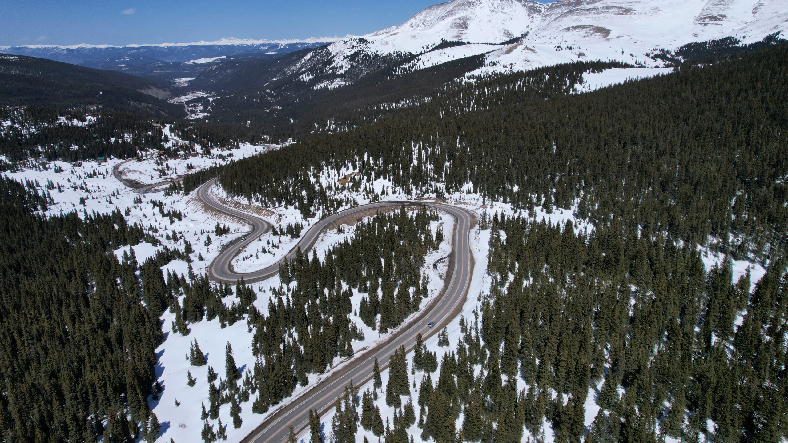 A road winds through the snow-covered Rocky Mountains at Hoosier Pass as seen from the air