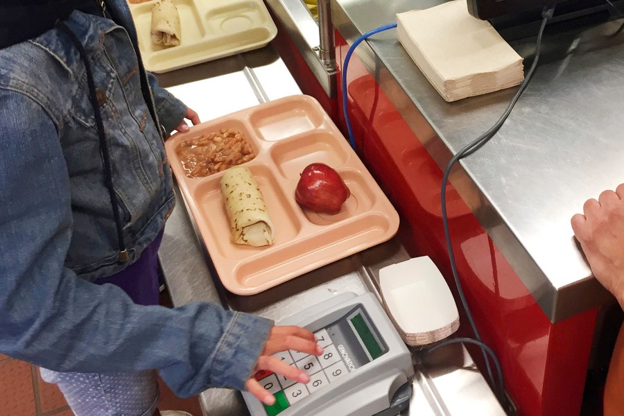 a child punches in her student identification to pay for a school meal