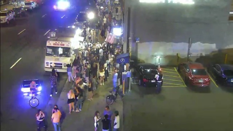 A crowded sidewalk beside a food truck and outside Larimer Beer Hall