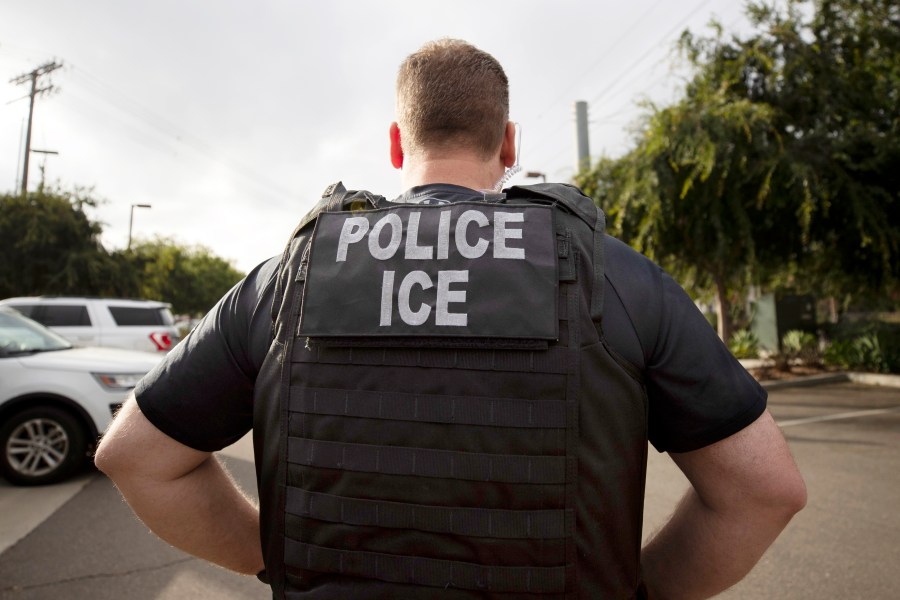 An U.S. Immigration and Customs Enforcement (ICE) officer in a police vest looks on during an operation