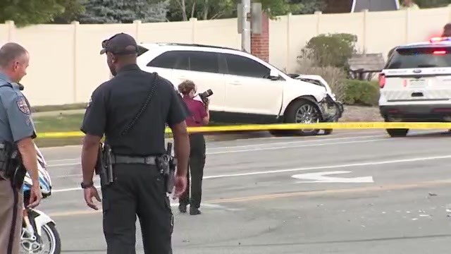 White SUV with front end damage with crime scene tap blocking the road and officers investigating