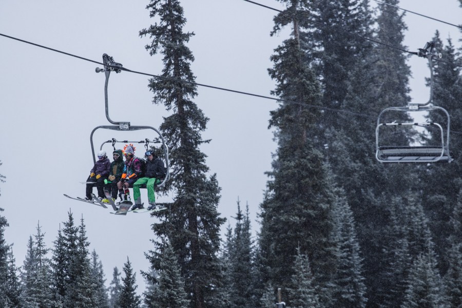 Skiers and boarders head up lift at A-basin on opening day