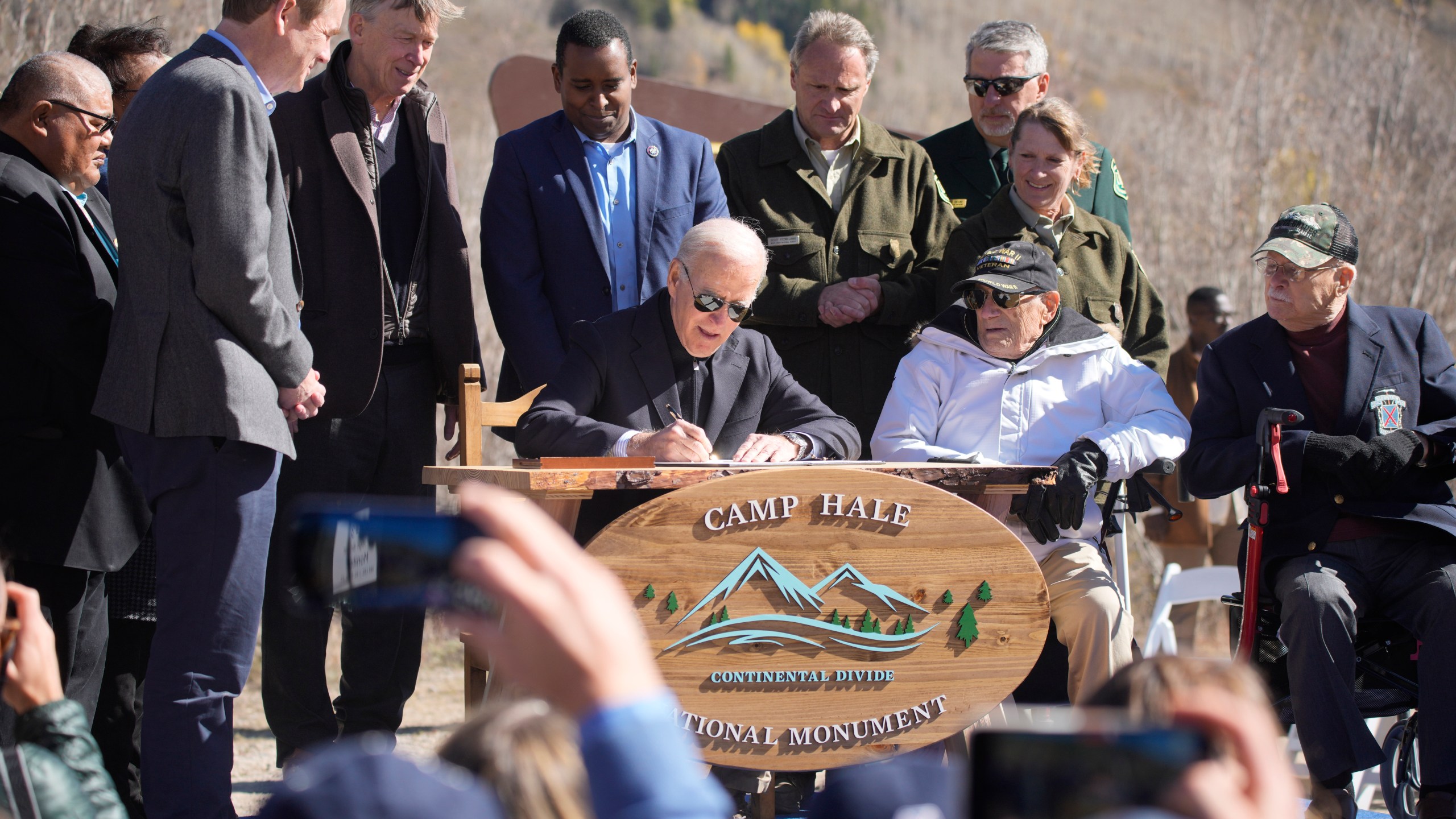 Michael Bennet, John Hickenlooper, Joe Neguse look on, President Joe Biden signs the papers