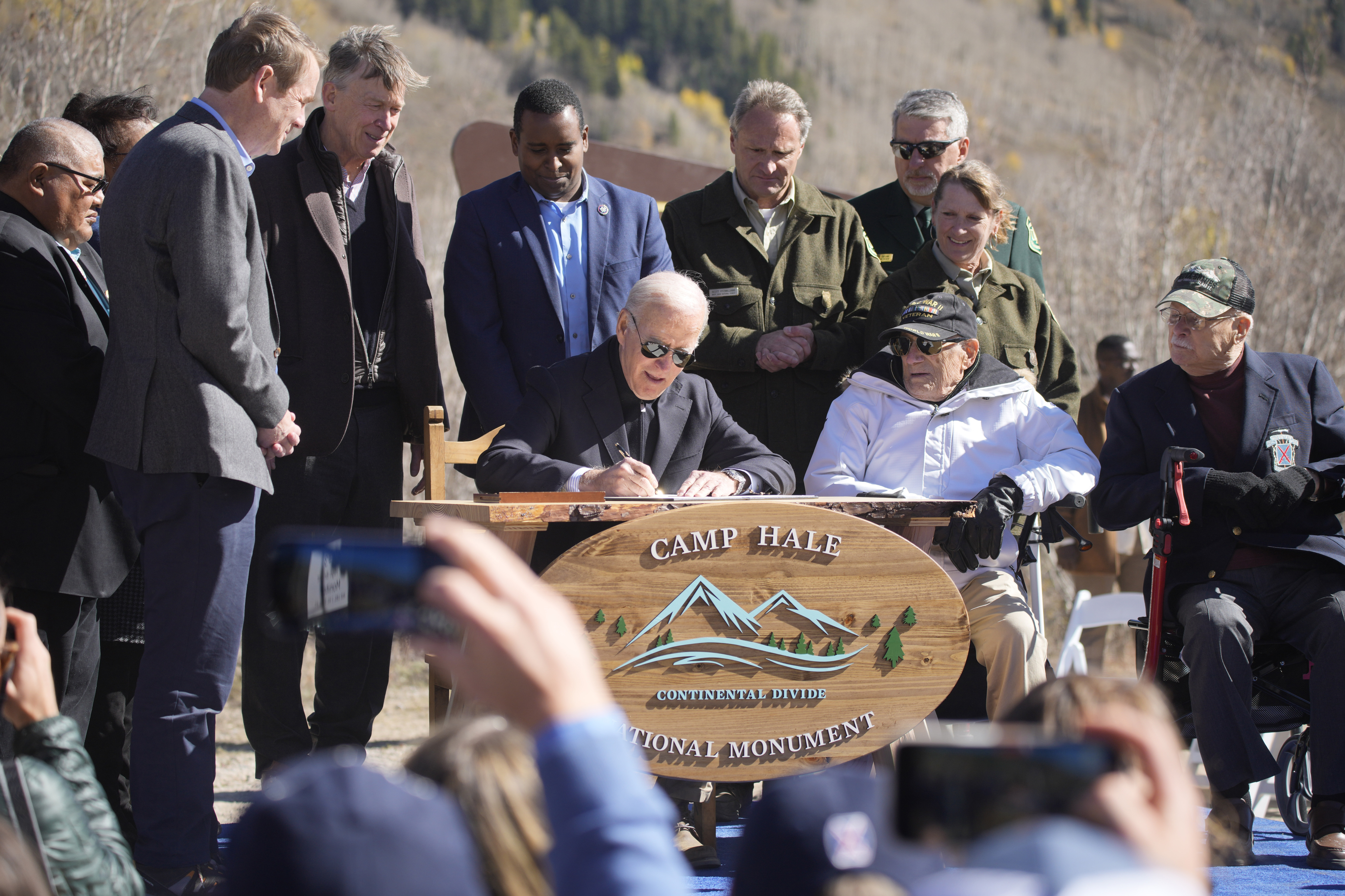 Michael Bennet, John Hickenlooper, Joe Neguse look on, President Joe Biden signs the papers