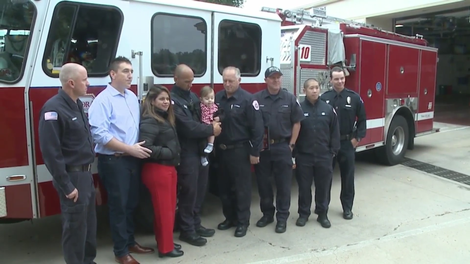 Group of people in front of fire truck with toddler