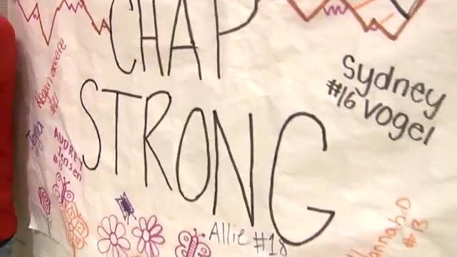 A poster reads "CHAP STRONG" in black market with doodles of flowers, player names and numbers