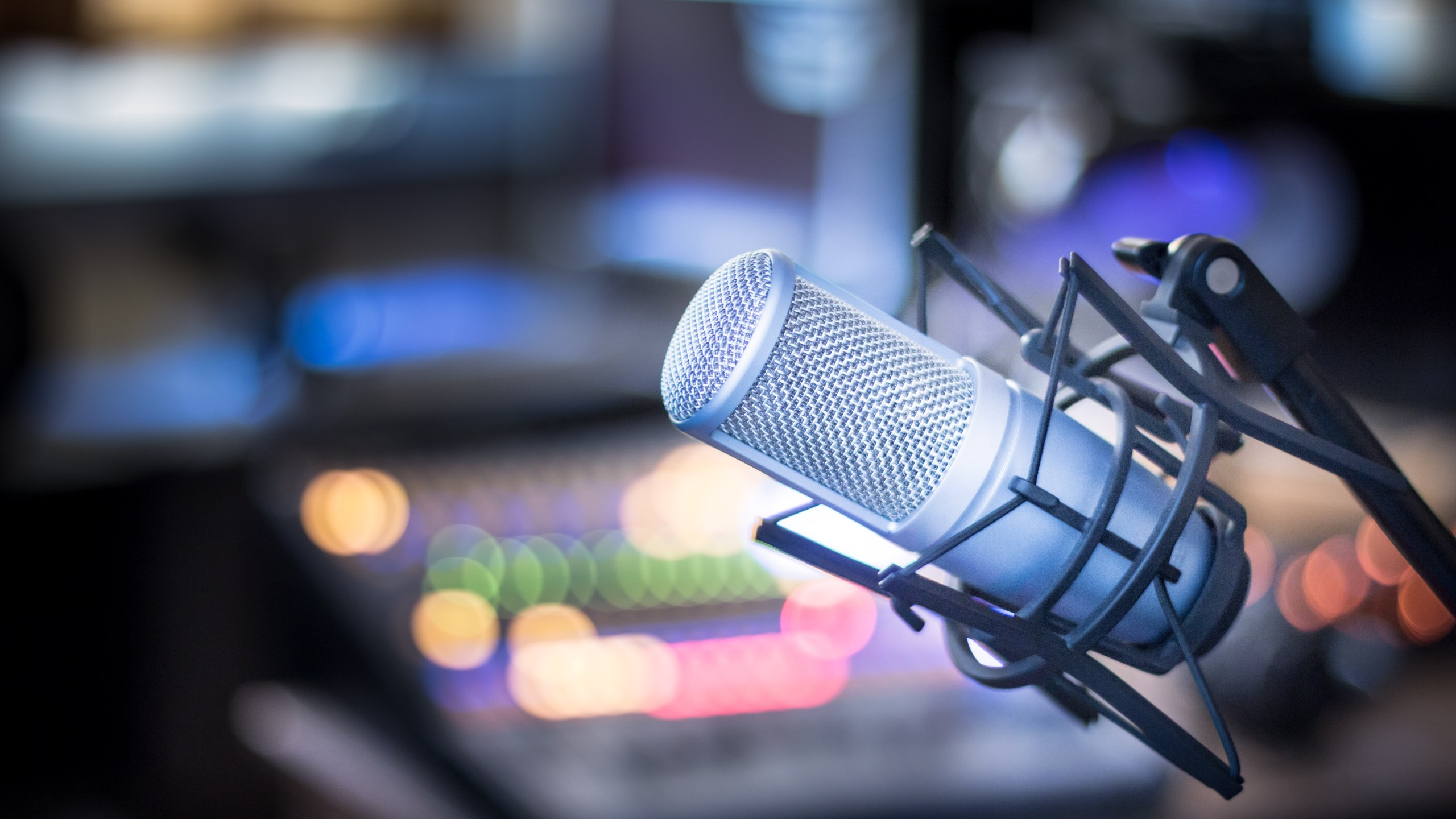 Microphone in a professional recording or radio studio, equipment in the blurry background