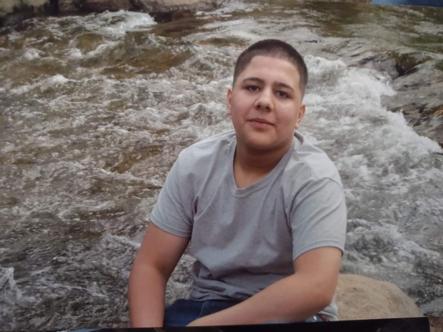 A boy looks into the camera while standing in outdoor water rapids