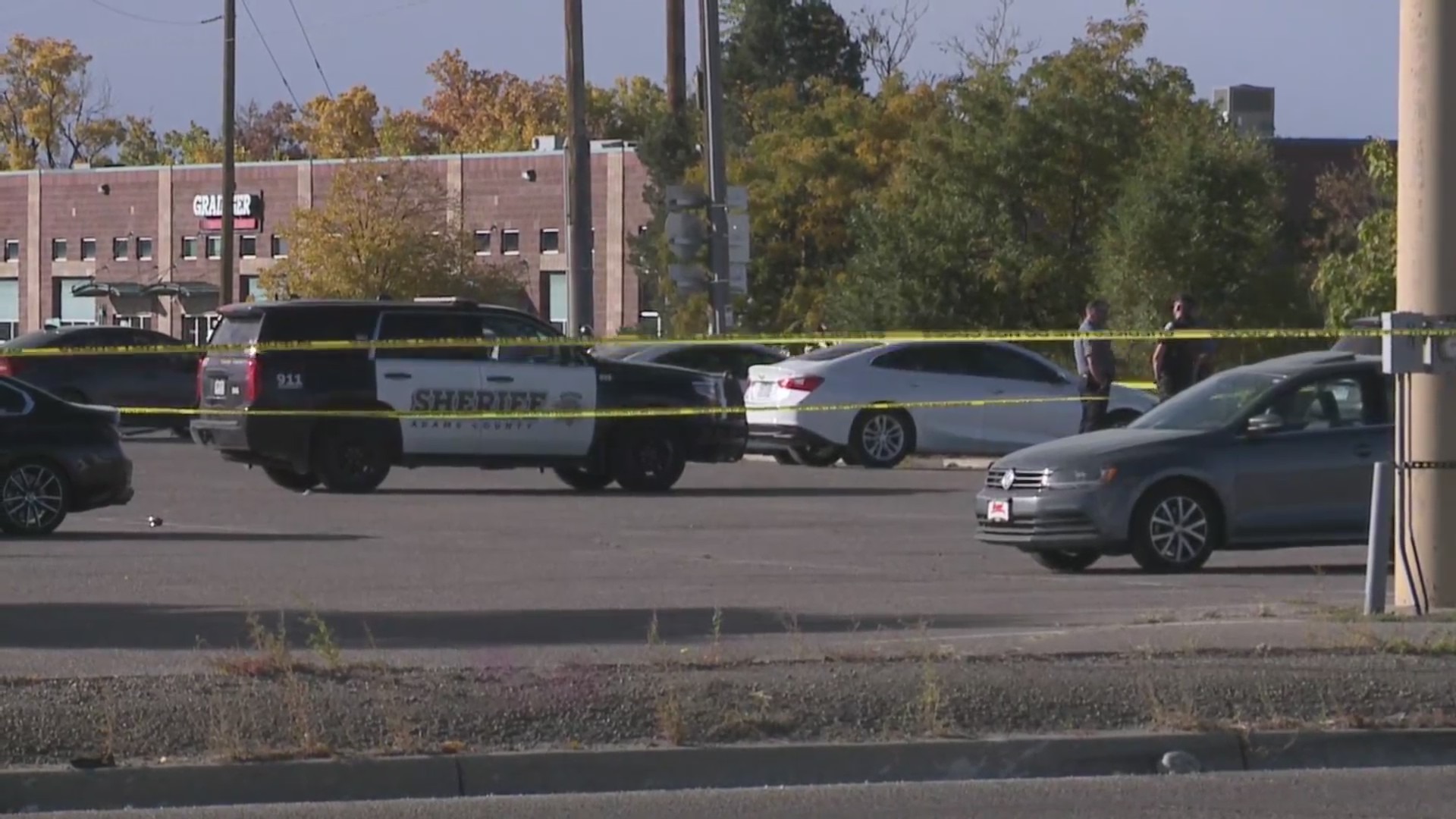 Crime scene tape and police vehicles in a parking lot