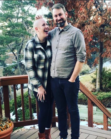 A smiling couple stand together outdoors