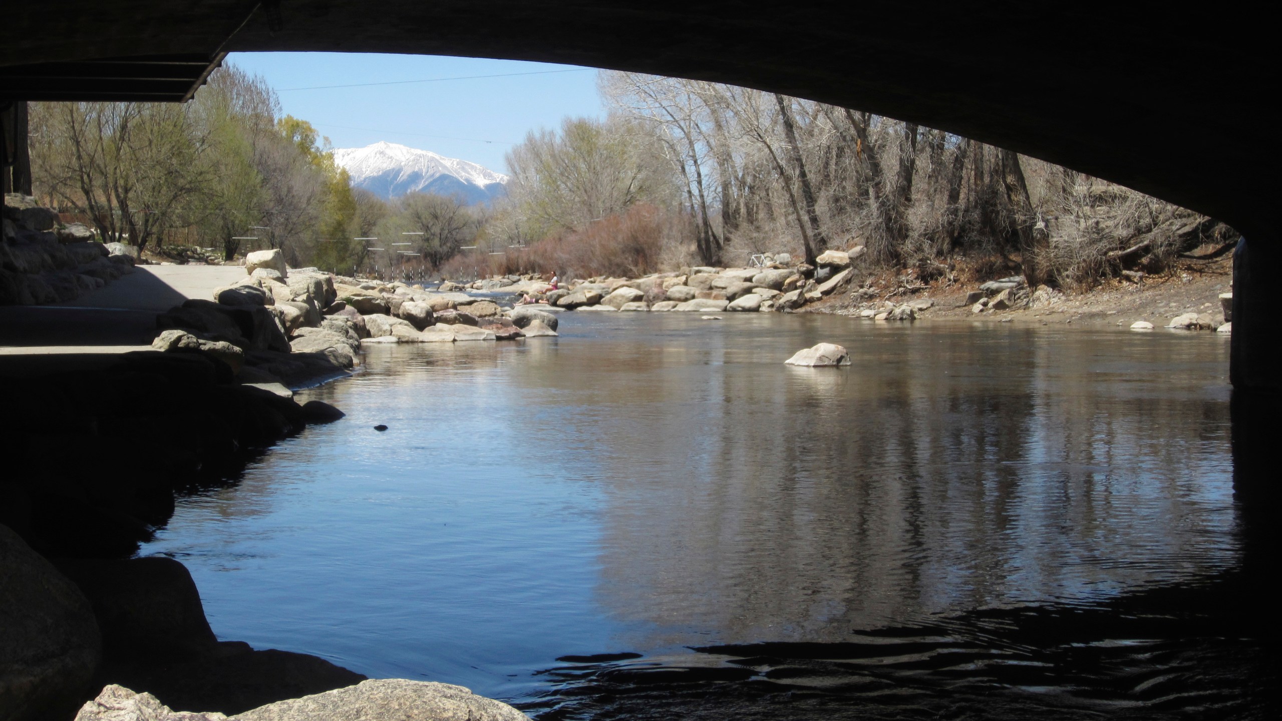 the Arkansas River flows under a bridge in Salida, Colo., with the snow-covered Sawatch Range mountains in the background