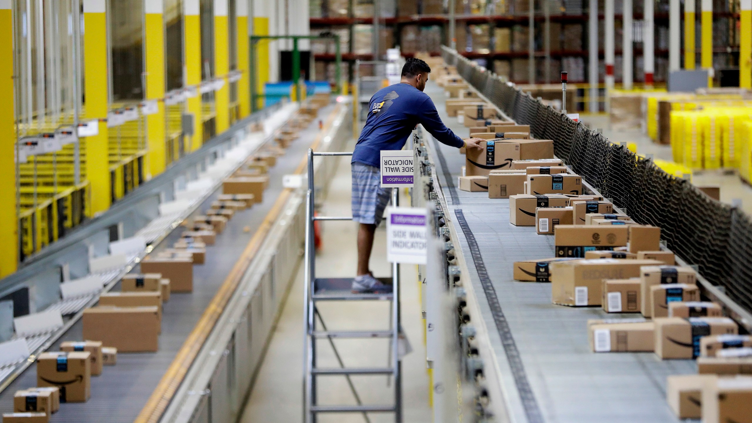 An Amazon employee makes sure a box riding on a belt is not sticking out at the Amazon Fulfillment center in Robbinsville Township, N.J.