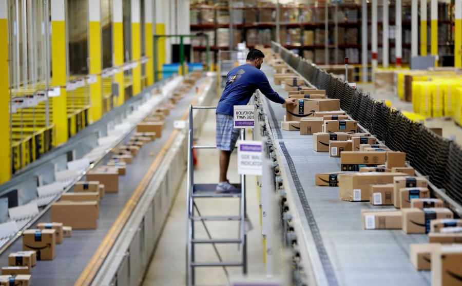 An Amazon employee makes sure a box riding on a belt is not sticking out at the Amazon Fulfillment center in Robbinsville Township, N.J.