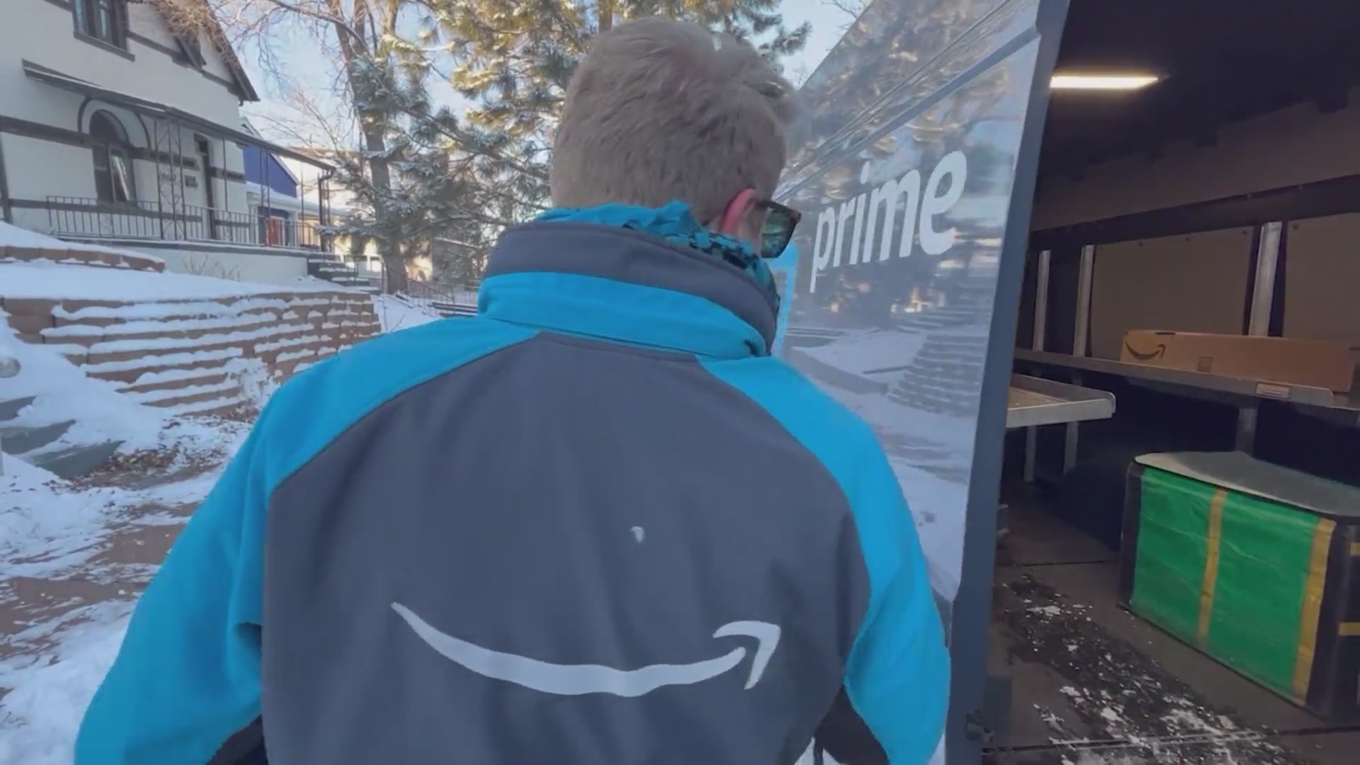 An Amazon delivery driver in uniform beside his open delivery van filled with packages