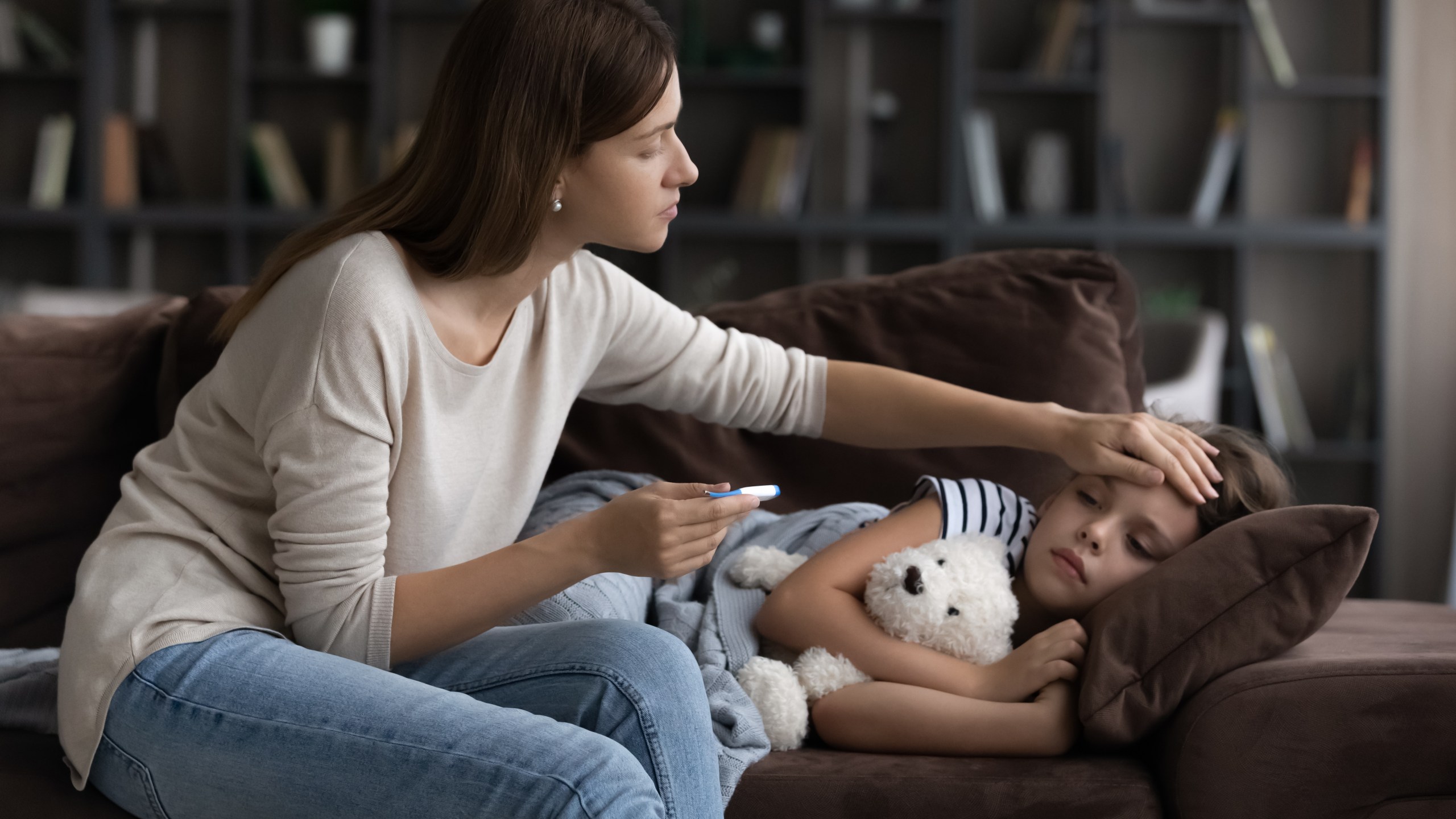 Concerned mother checking high body temperature of daughter