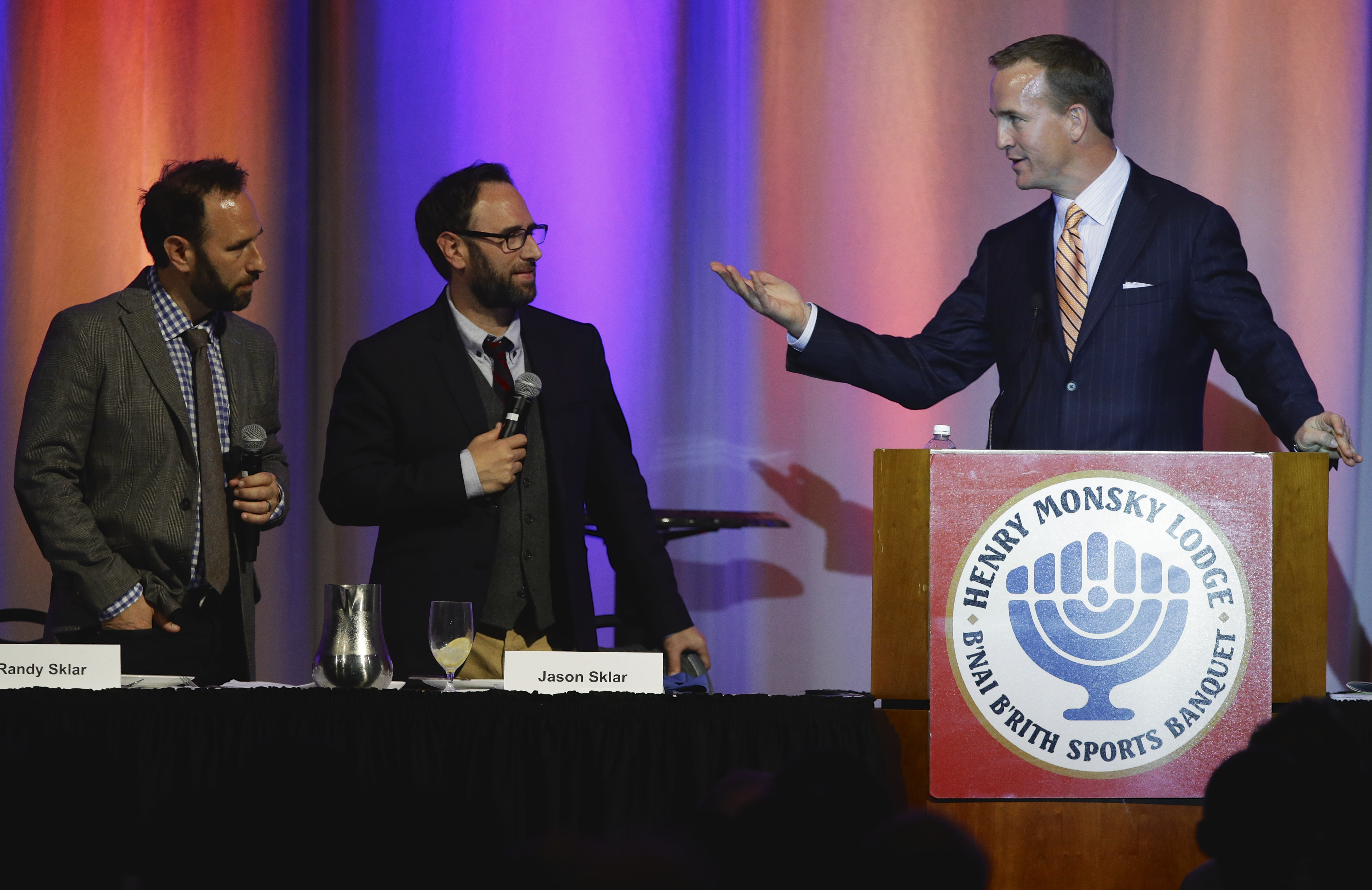 Denver Broncos quarterback Peyton Manning points to comedians Randy Sklar, left, and twin brother Jason, second left, as he speaks