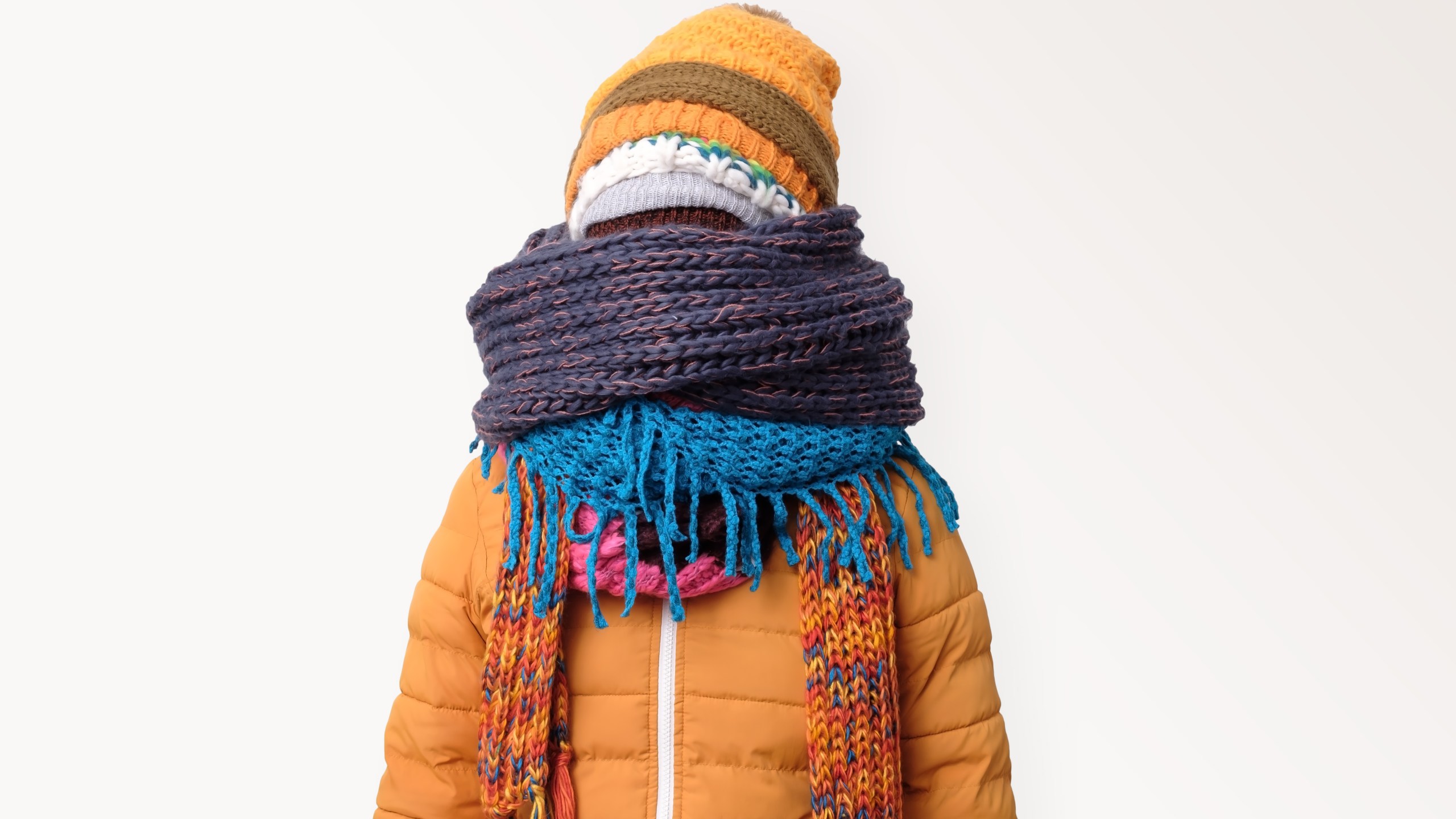 Handsome caucasian funny man hiding face in several hats and scarfs.