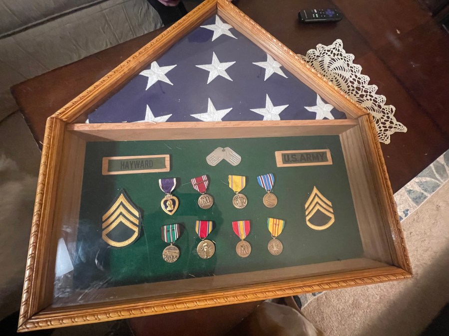 A frame with a folded US flag and numerous military medals from WWII, Vietnam